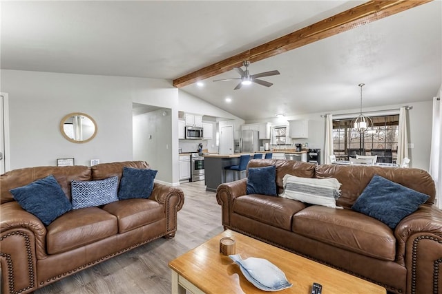 living room with lofted ceiling with beams, ceiling fan with notable chandelier, and light hardwood / wood-style flooring