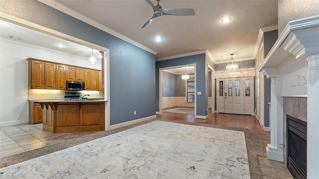 kitchen with kitchen peninsula, decorative light fixtures, ceiling fan, crown molding, and a kitchen breakfast bar