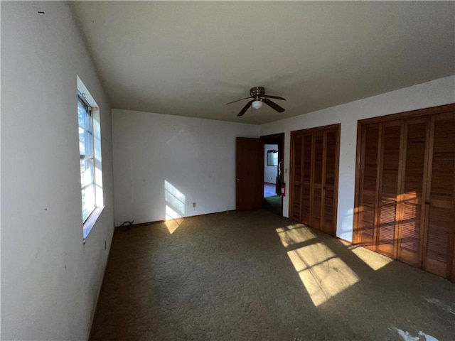 unfurnished bedroom with ceiling fan, multiple closets, and carpet flooring