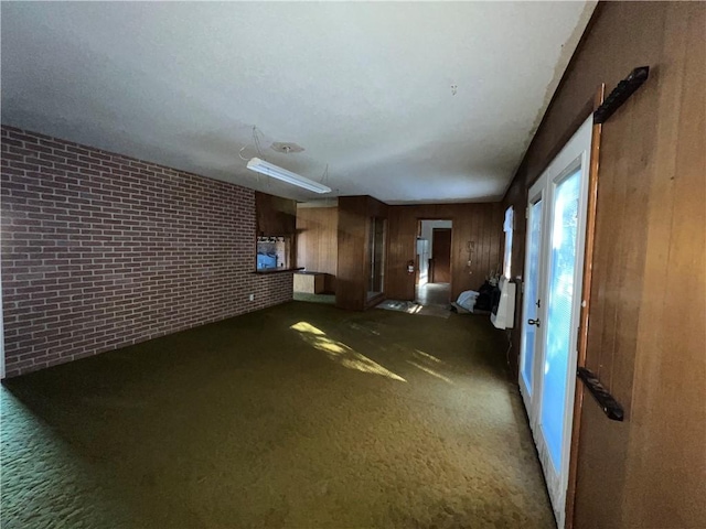 unfurnished living room with dark carpet and brick wall