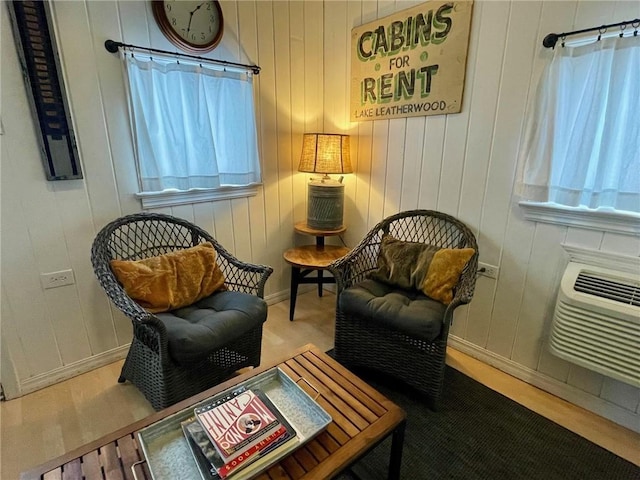 sitting room with a wall mounted air conditioner and wood-type flooring