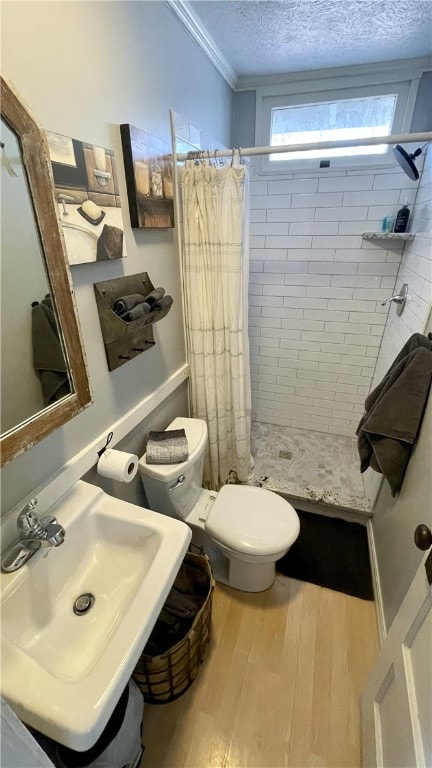 bathroom with a shower with curtain, a textured ceiling, hardwood / wood-style floors, ornamental molding, and sink