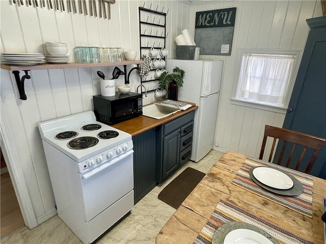 kitchen featuring sink, white appliances, blue cabinets, and butcher block counters