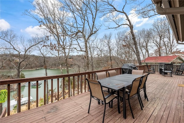 deck with outdoor dining area, a water view, and area for grilling