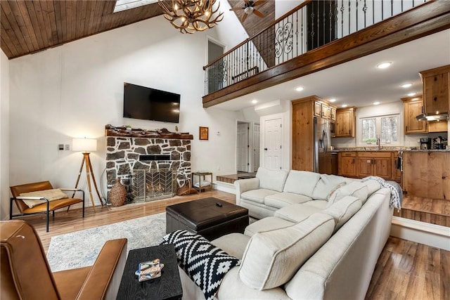 living room with a fireplace, wood ceiling, wood finished floors, high vaulted ceiling, and baseboards