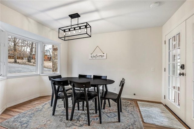 dining area featuring light wood-type flooring, french doors, and baseboards