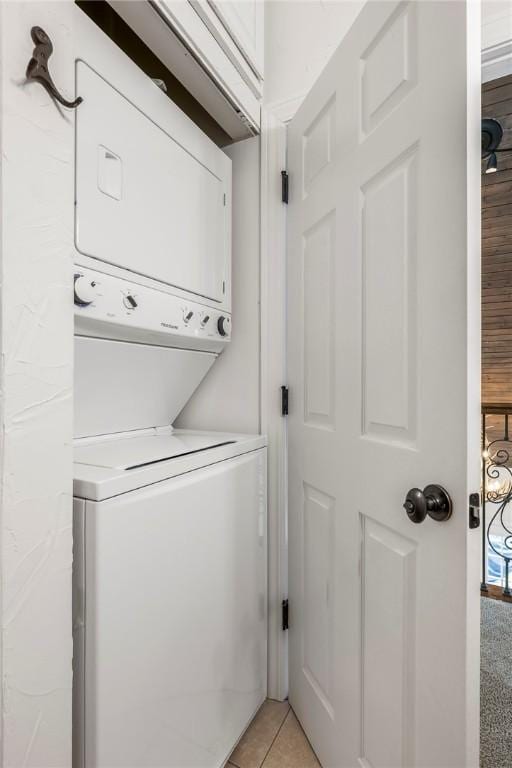 clothes washing area featuring stacked washer / dryer, laundry area, and light tile patterned floors