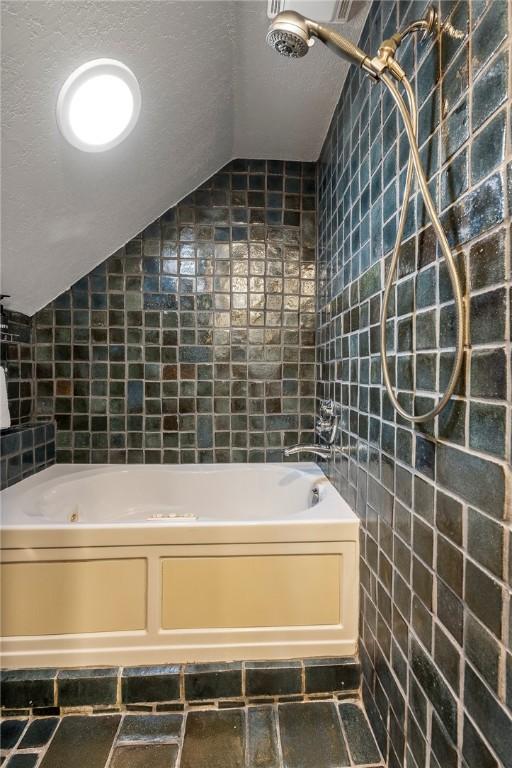 bathroom featuring lofted ceiling, tile walls, and a textured ceiling