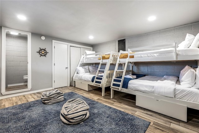 bedroom with recessed lighting, concrete block wall, and wood finished floors