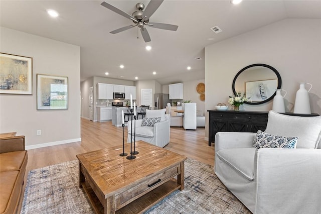 living room with ceiling fan, vaulted ceiling, and light hardwood / wood-style floors