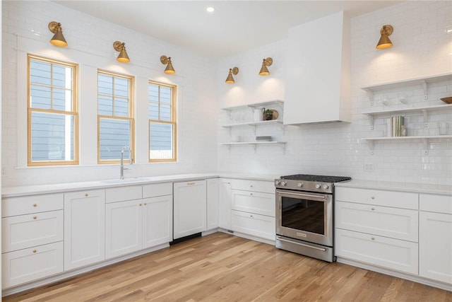 kitchen featuring sink, white cabinetry, stainless steel gas range oven, and light hardwood / wood-style flooring