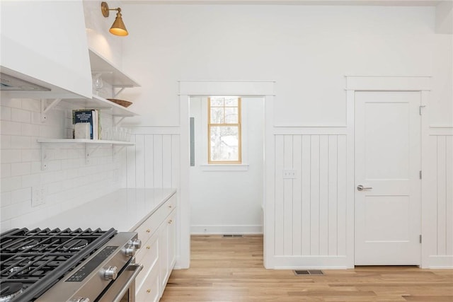 kitchen featuring light wood-type flooring, open shelves, light countertops, and stainless steel gas stove