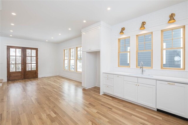 kitchen with white cabinets, a sink, recessed lighting, light wood-style floors, and dishwasher