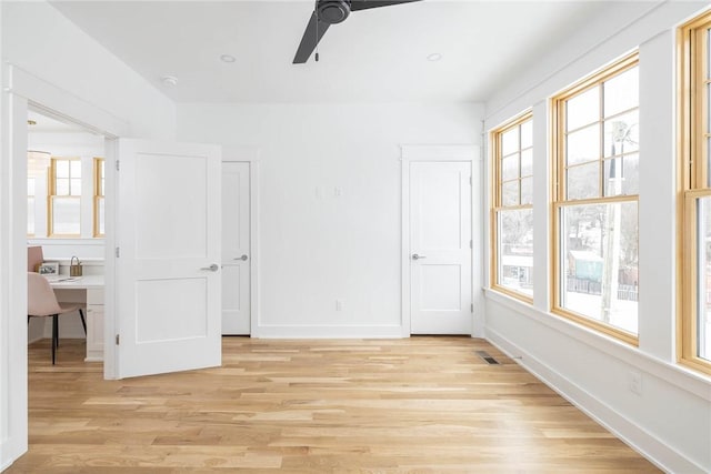 unfurnished bedroom with light wood-type flooring, visible vents, a ceiling fan, and baseboards