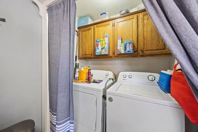 washroom with washing machine and clothes dryer, cabinets, and a textured ceiling