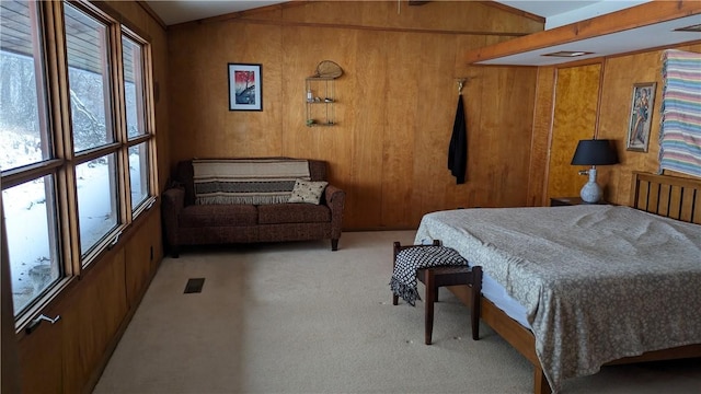 carpeted bedroom with vaulted ceiling, wood walls, and visible vents