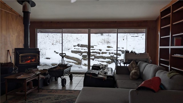 living room featuring wooden walls, a wood stove, and tile patterned floors