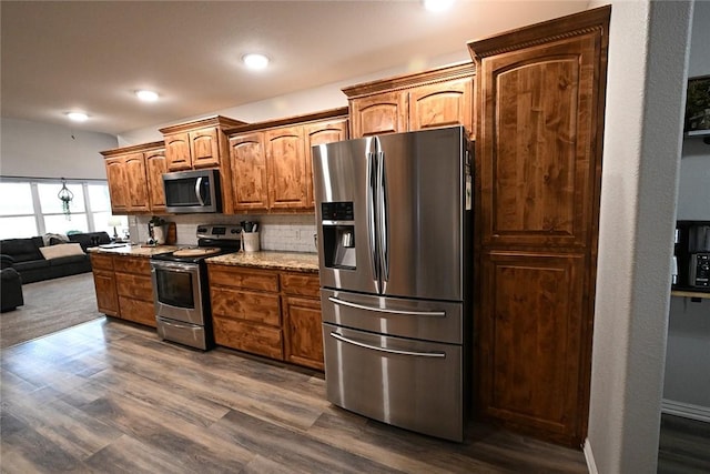 kitchen featuring light stone counters, tasteful backsplash, stainless steel appliances, and dark hardwood / wood-style flooring