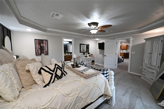 carpeted bedroom featuring ornamental molding, ensuite bath, ceiling fan, and a raised ceiling