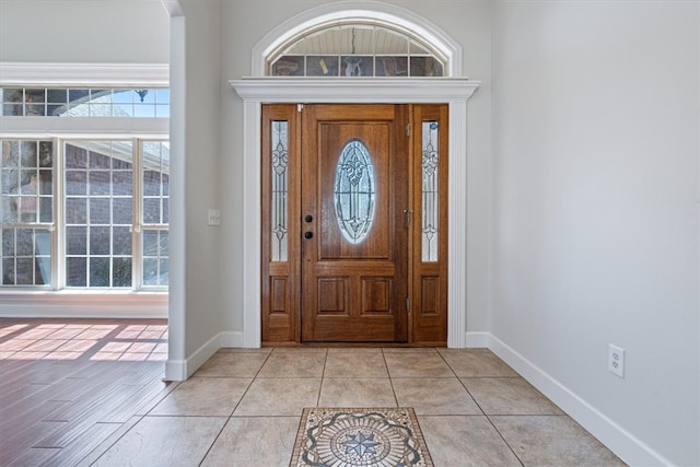 foyer with plenty of natural light, light tile patterned flooring, and baseboards