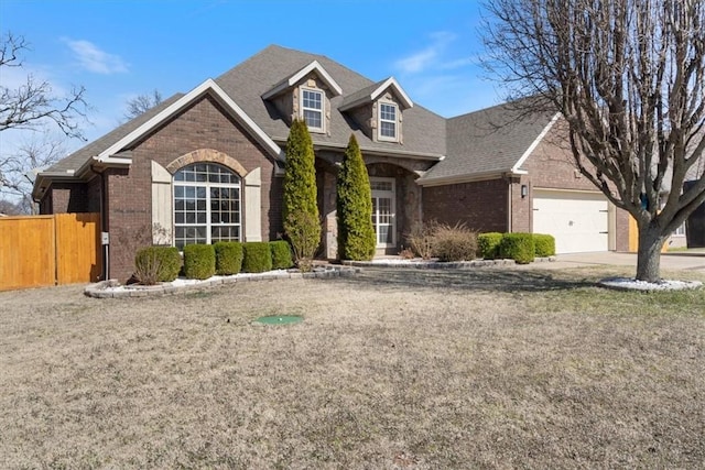 view of front of property with brick siding, roof with shingles, fence, a garage, and driveway