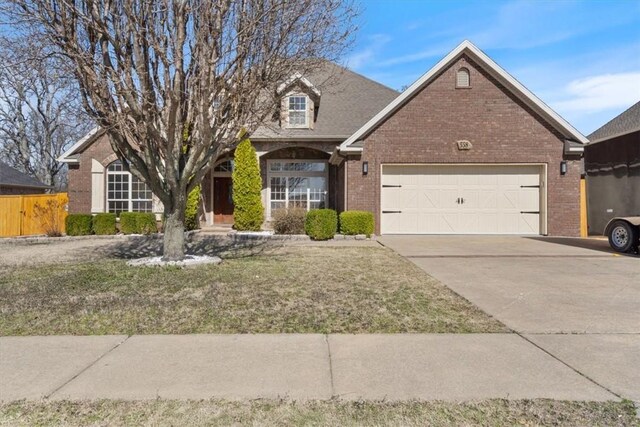 view of front of home featuring an attached garage, fence, concrete driveway, and brick siding