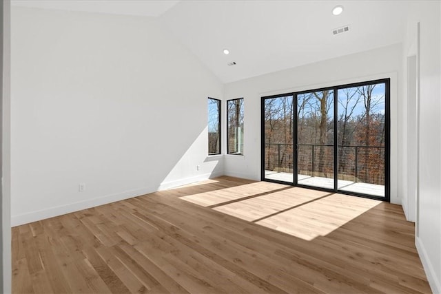 empty room with high vaulted ceiling, light wood-type flooring, and a wealth of natural light