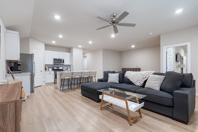 living area with light wood-type flooring, a ceiling fan, and recessed lighting