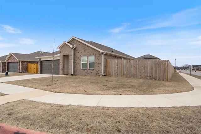 view of front of home with a garage, driveway, fence, a front lawn, and brick siding