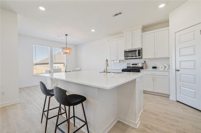 kitchen with white cabinetry, stainless steel appliances, a kitchen island with sink, and sink