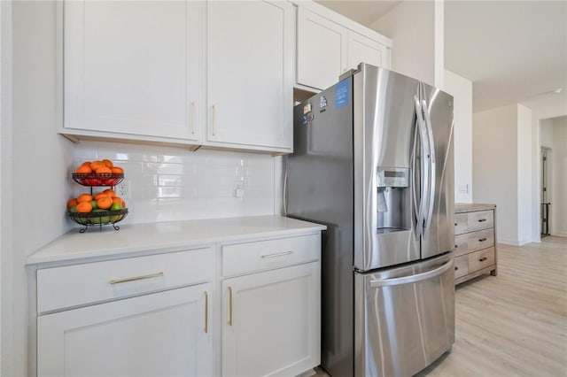 kitchen featuring white cabinetry, backsplash, stainless steel fridge, and light hardwood / wood-style flooring