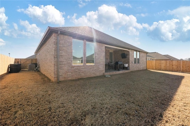 rear view of property featuring a patio, a yard, and central AC