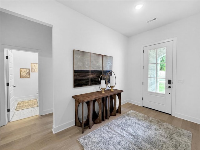 foyer featuring baseboards, visible vents, and wood finished floors