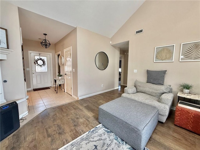 foyer entrance with light hardwood / wood-style floors, high vaulted ceiling, and a chandelier