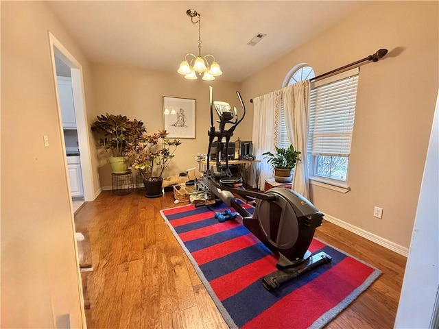 workout room featuring a notable chandelier and wood-type flooring