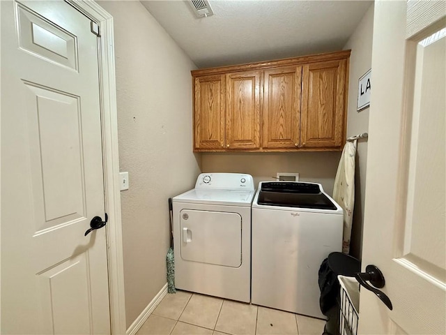 clothes washing area with cabinets, separate washer and dryer, and light tile patterned floors