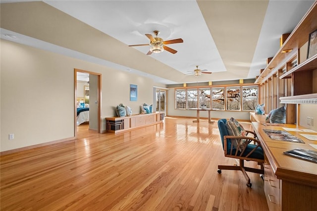 office space with a raised ceiling, ceiling fan, baseboards, and wood finished floors