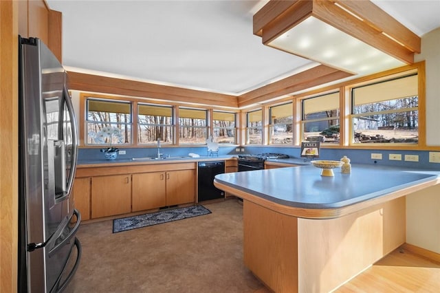 kitchen featuring black appliances, a peninsula, a sink, and a wealth of natural light