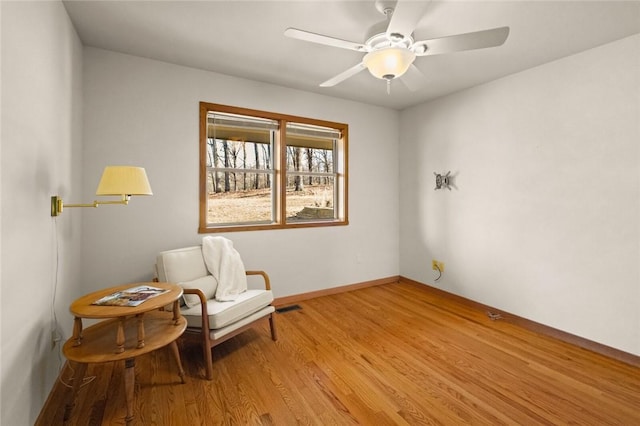 living area with ceiling fan, baseboards, visible vents, and light wood-style floors