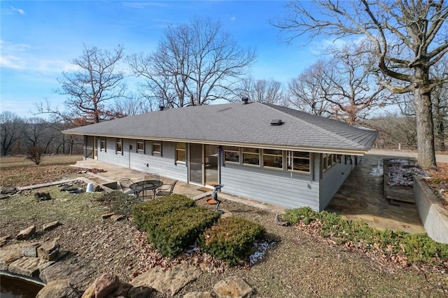 view of front of home featuring roof with shingles and a patio