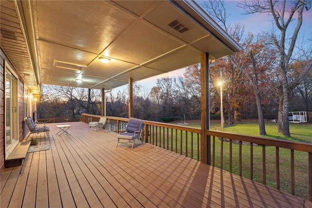 deck at dusk featuring a yard