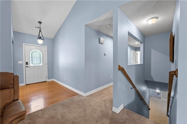 entryway featuring a textured ceiling, light carpet, and lofted ceiling