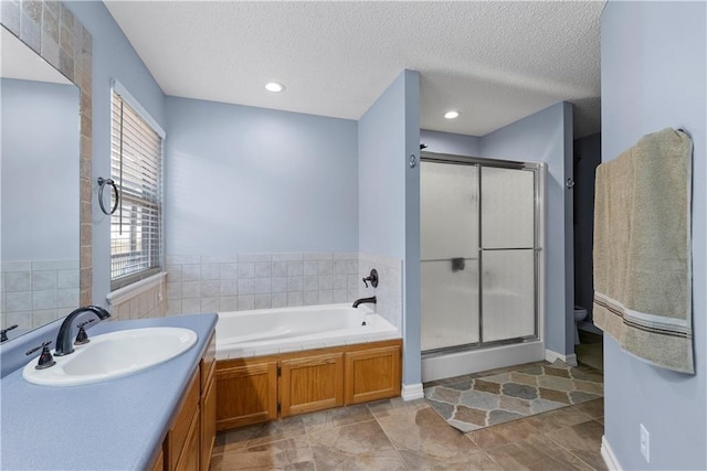 full bathroom with vanity, independent shower and bath, toilet, and a textured ceiling