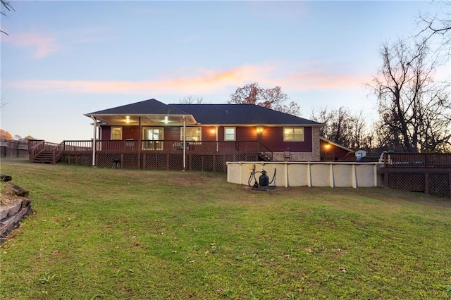 back house at dusk featuring a yard and a swimming pool side deck