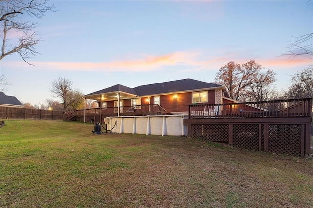 back house at dusk featuring a yard and a pool side deck