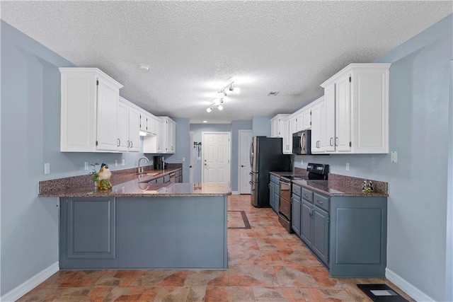 kitchen featuring white cabinets, dark stone countertops, stainless steel appliances, and sink