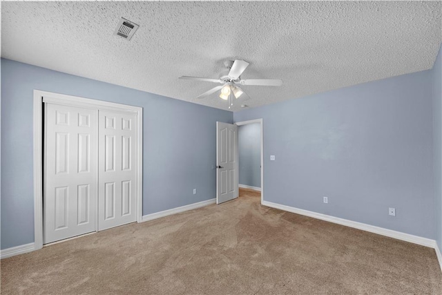 unfurnished bedroom with ceiling fan, a closet, a textured ceiling, and light colored carpet