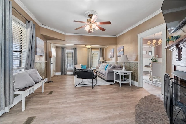 living room with ceiling fan with notable chandelier, light hardwood / wood-style floors, and ornamental molding