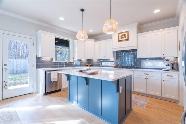 kitchen with appliances with stainless steel finishes, a breakfast bar area, white cabinets, decorative light fixtures, and a kitchen island