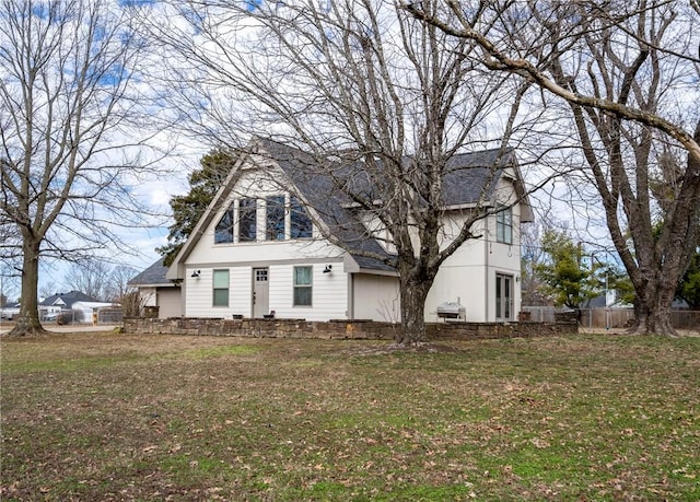 view of front of home featuring a shingled roof, fence, and a front yard